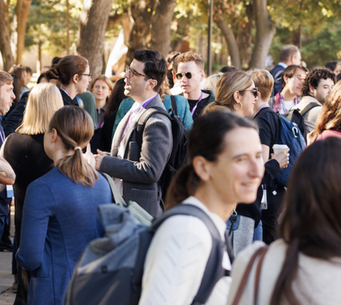 crowd of people at a conference talking and smiling outdoors