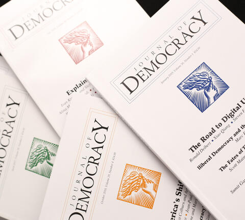 Spread of issues of the Journal of Democracy on black background