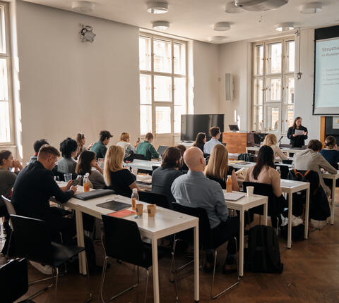 Students sitting at desk watch a lecture