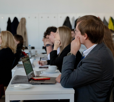 Students taking notes and listening during an academic seminar.
