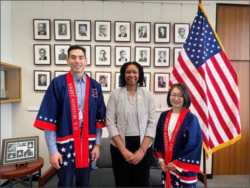 three people standing in front of an American flag with two people wearing a happi