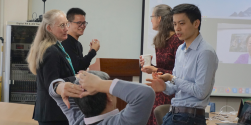 Two women and three men talking with each other in a conference room