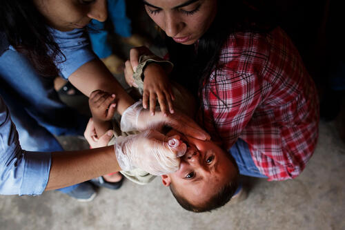 Two nurses give a crying child the Oral polio vaccine in a corner in a Syrian refugee camp in Suruc September 28, 2014 south of Sanliurfa, Turkey. (Photo by Carsten Koall/Getty Images) syria polio