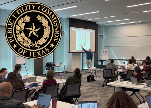 Frank Wolak points to a graph on a screen in front of an audience seated around tables