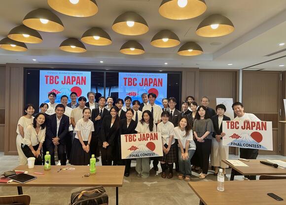 a group of students standing with signs, "TBC Japan"