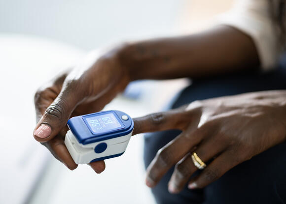 Photo of a dark-skinned woman using a pulse oximeter