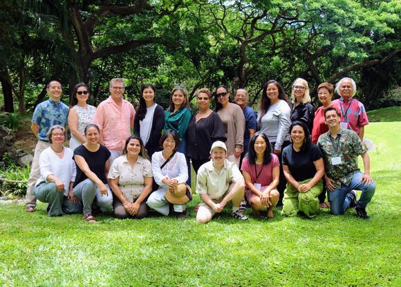 group of educators posing in front of a lush green canopy