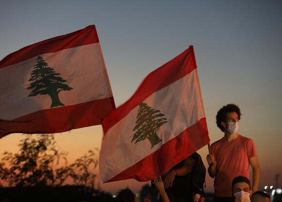 Picture of Lebanese protester in Mask with two flags. 