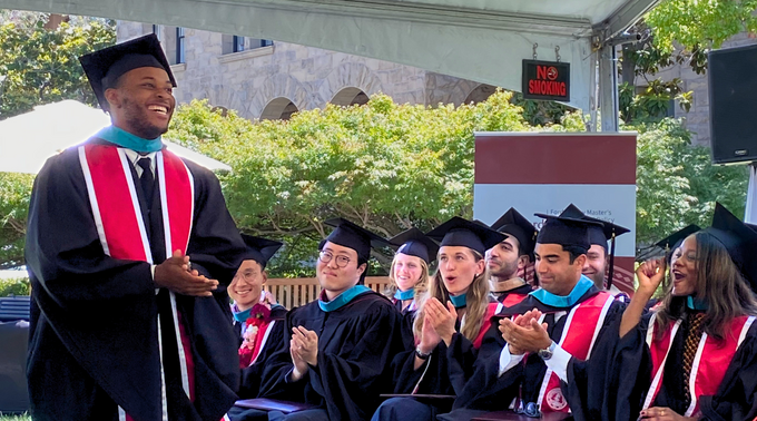 Tyler Smith, a graduate of the Class of 2026 of the Ford Dorsey Master's in International Policy, walks past his applauding classmates to receive his diploma.