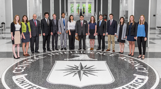 Students from the 2014-15 cohort of the CISAC Undergraduate Honors Program stand around the logo of the Central Intelligence Agency in the atrium of CIA headquarters in Langley, Virginia.