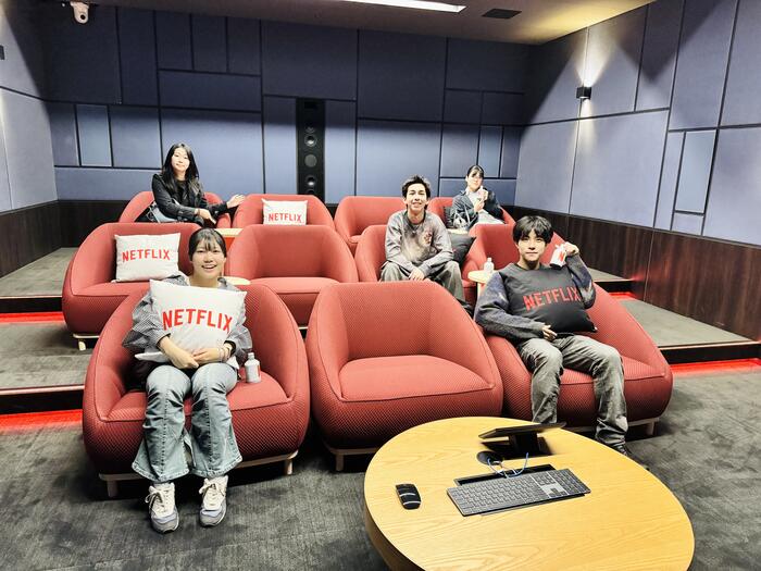 five people sitting on red chairs
