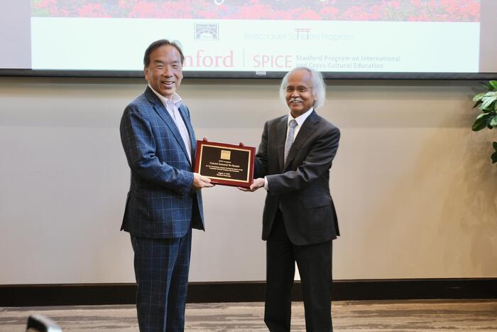 two people holding a plaque in front of a screen