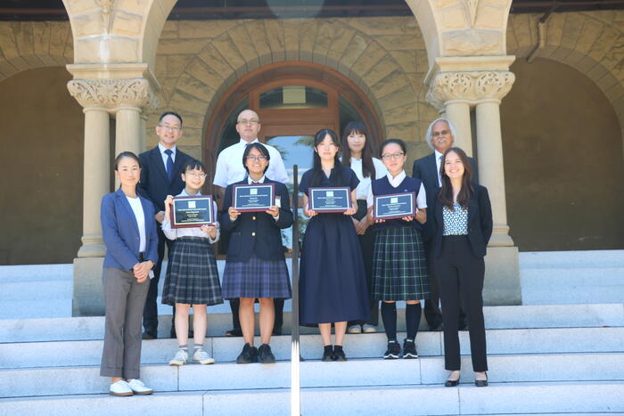 students holding plaques standing at the staircase