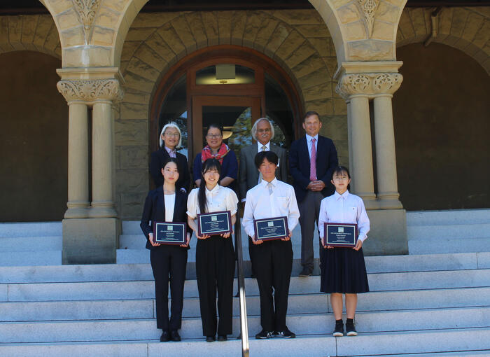 students holding plaques standing at the staircase