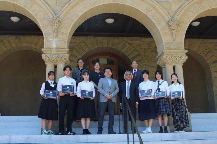 students holding plaques standing at the staircase