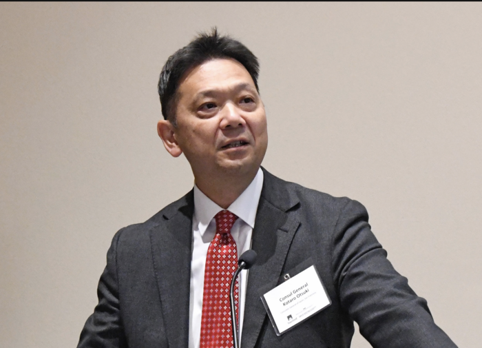 a person in a suit speaking at a podium