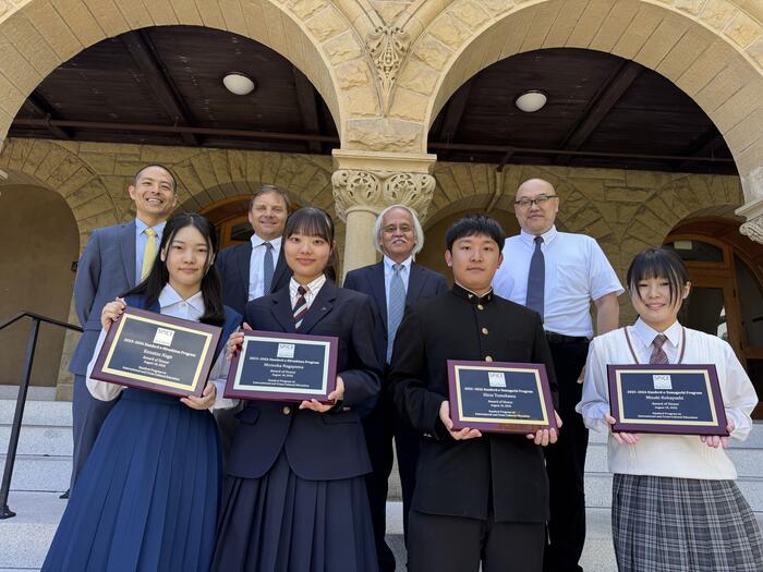 students with plaques standing outside of Encina Hall at Stanford