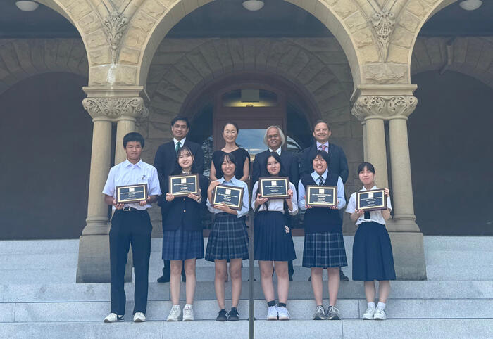 students with plaques standing outside of Encina Hall at Stanford