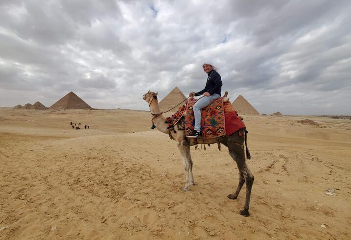 Luis Sanchez rides a camel in front of the Great Pyramids in Egypt.