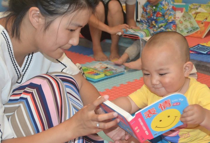 A caregiver reads to a baby.