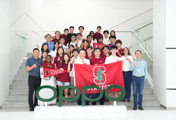 Group photo of students, staff, and faculty in China with Stanford flag. 