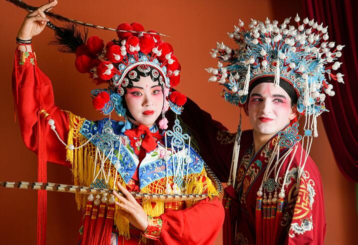 Two students dress up in Chinese opera attire and makeup and pose.