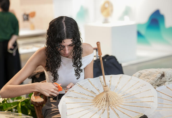 A young woman makes a paper umbrella. 