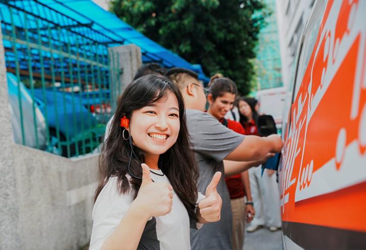 A student gives the camera a double thumbs up.