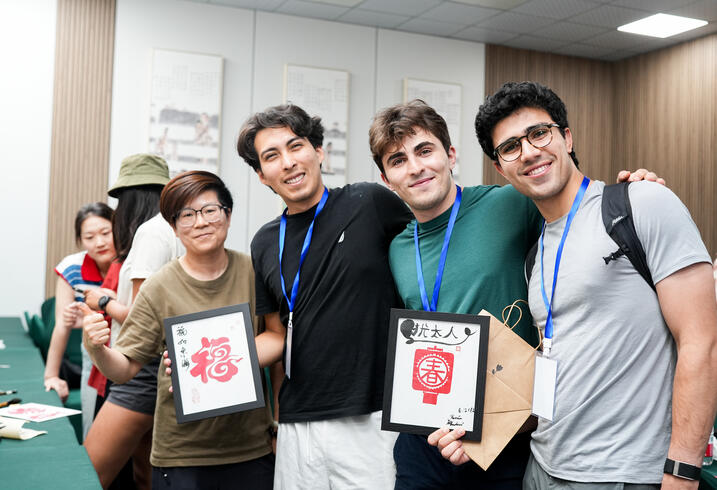 Students pose with framed paper cuttings.