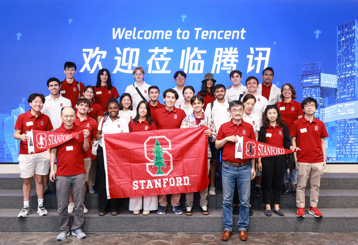Group photo of students, staff, and faculty in China with Stanford flag at Tencent.. 