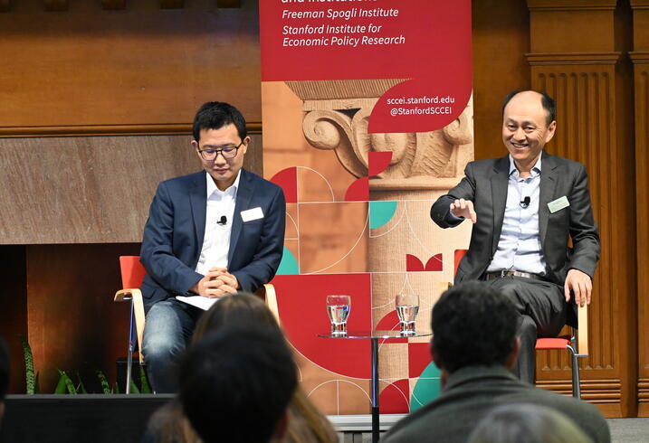 Yiqing Xu and Hongbin Li sit on a stage during a SCCEI event.