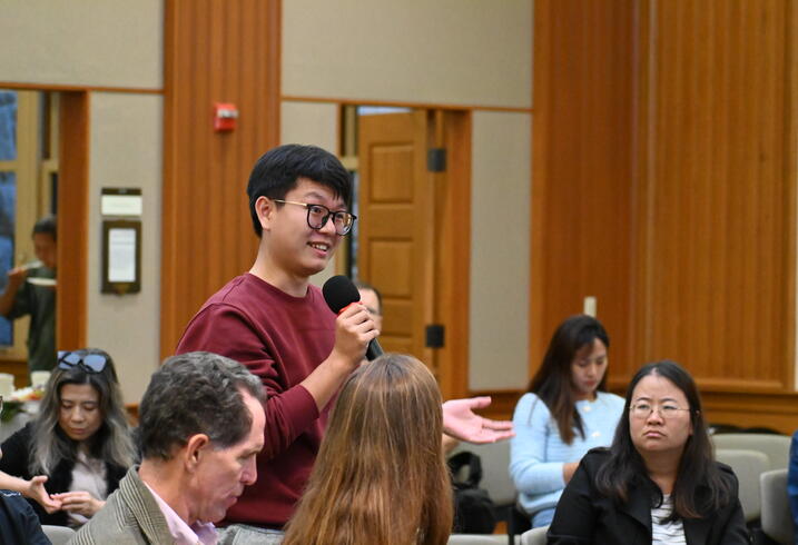 A student asks a question from the audience of an event.