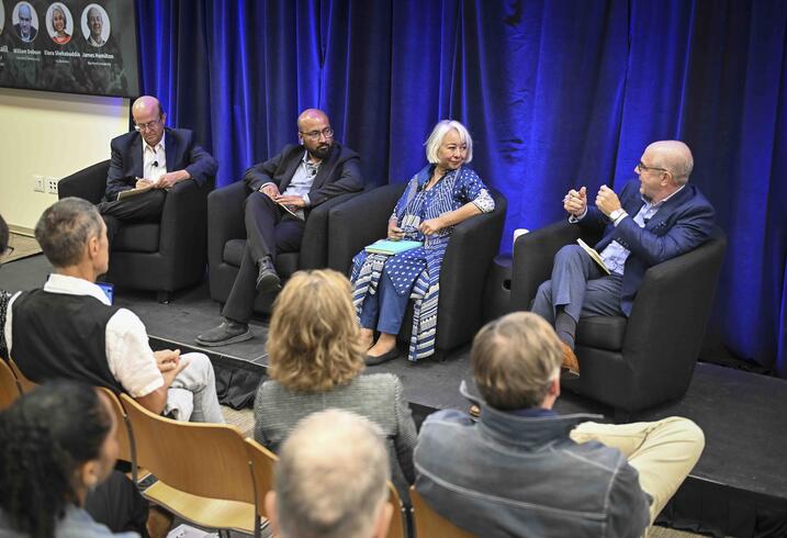 Four panelists seated on stage in a conference room having a discussion.