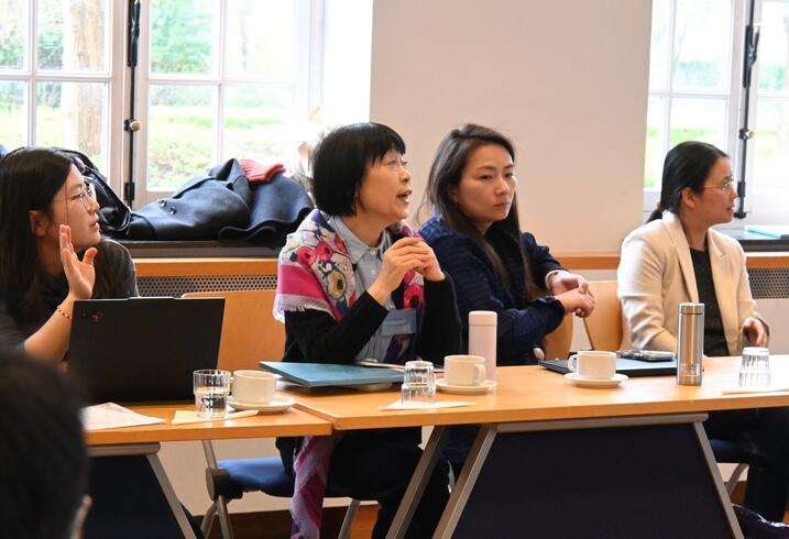 Women sit at a table and engage in conversation during a conference session.