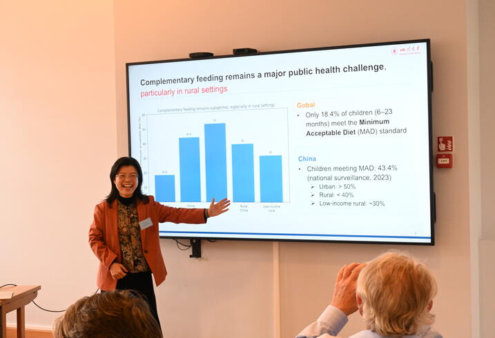 A woman presents data on a large screen in a conference room.