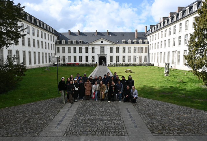 A group of conference attendees pose in a grand courtyard.