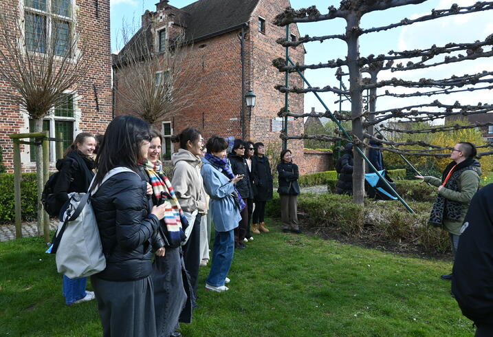 A group stands outside listening to a guide.