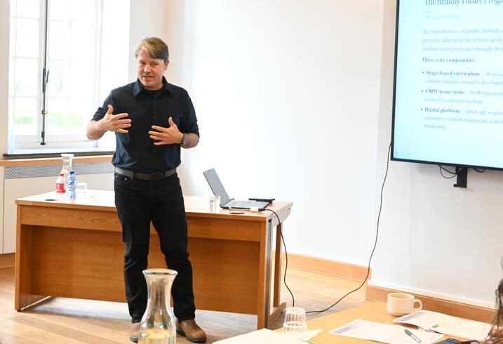 A man presents at the front of a conference room.