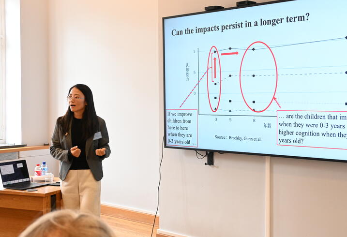 A woman presents data on a large screen in a conference room.
