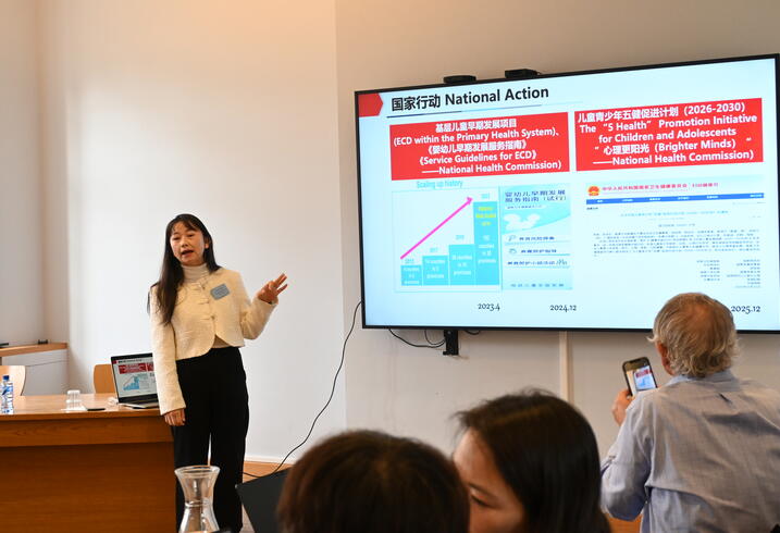 A woman presents data on a large screen in a conference room.