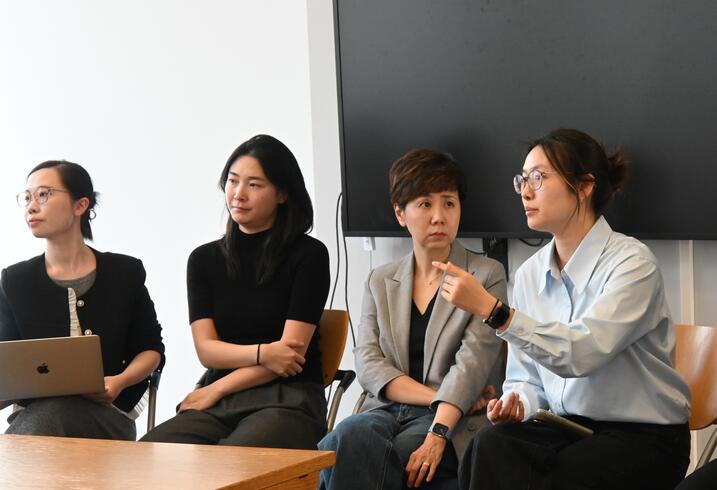 A group of women sit in discussion in a conference room.