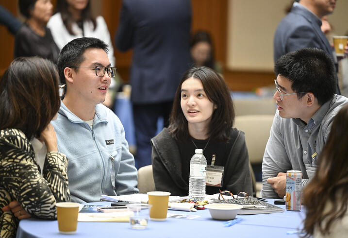 Students sit at a table and talk during a conference break.