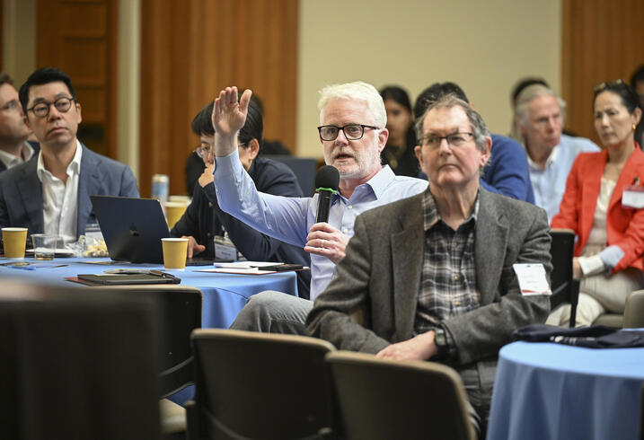 An audience member speaks into a handheld mic from an event audience.