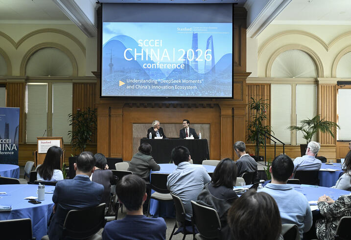 A full room of attendees seated at round tables during a conference. 