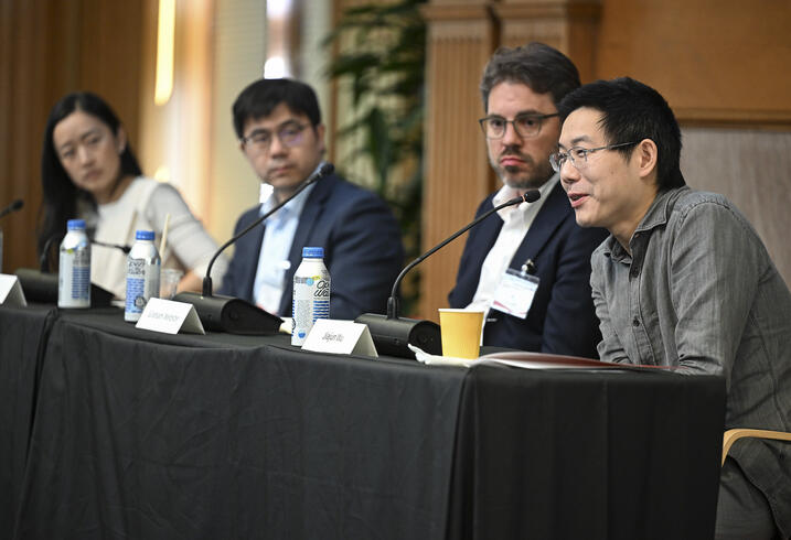 A group of people sit behind a table on a panel session at a conference.
