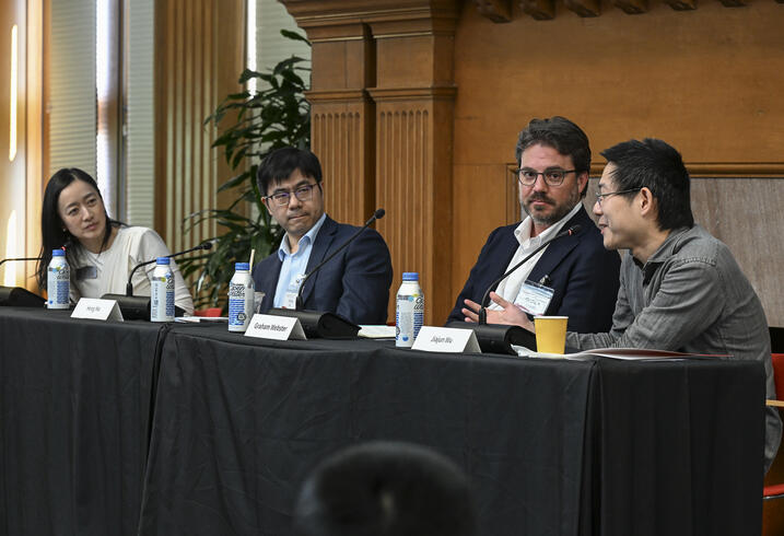 A group of four people sit at a table on stage during a panel discussion.