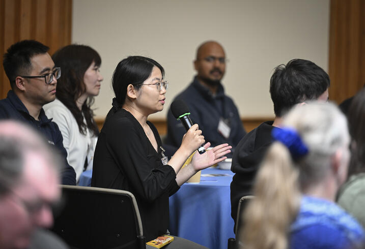 An audience member speaks into a handheld mic from an event audience.