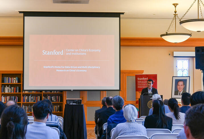 Yiqing Xu speaks at the front of a lecture room and seated audience.