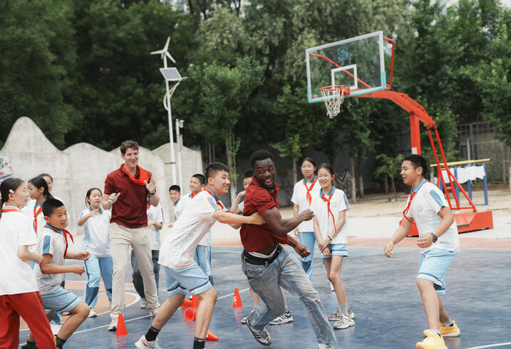 Kids play basketball outdoors.