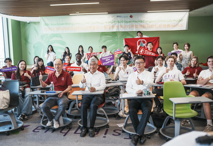 Students and teachers pose for a photo seated in a classroom.
